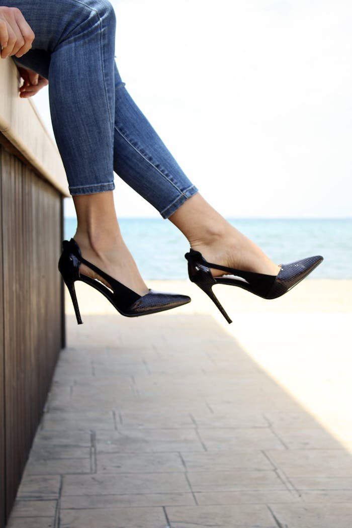 Stylish high heels with jeans against a serene seaside background in Thessaloniki.